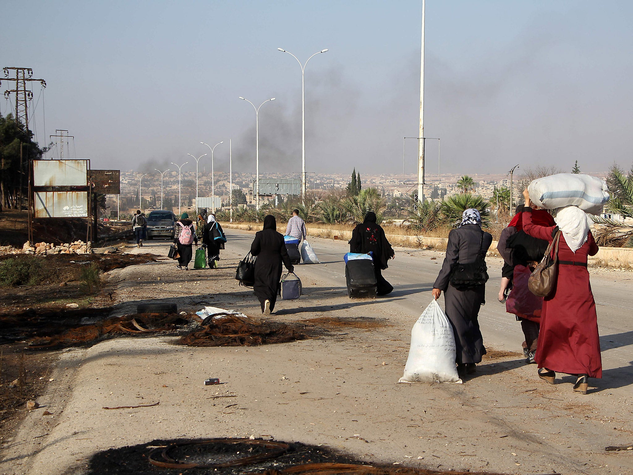 Syrians carry their belongings as they leave the southwestern frontline neighbourhood of Dahiyet al-,Assad