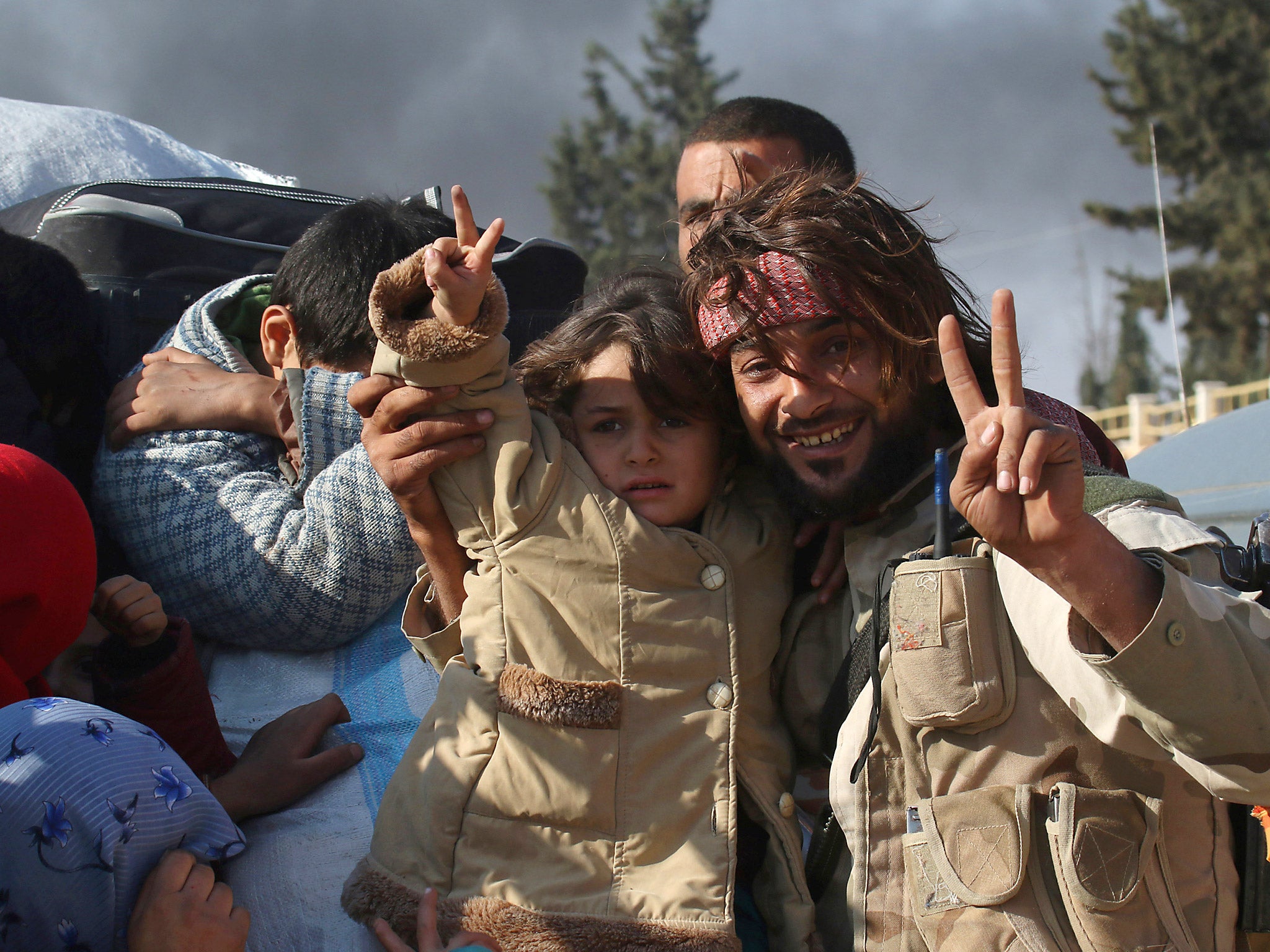 A rebel fighter gestures with a girl who fled areas of conflict while they ride a pick-up truck in Dahiyet al-Assad