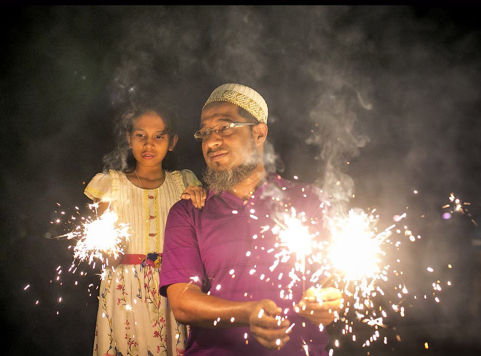 A man and his daughter hold fire cracker as Indians celebrate the annual festival of Diwali