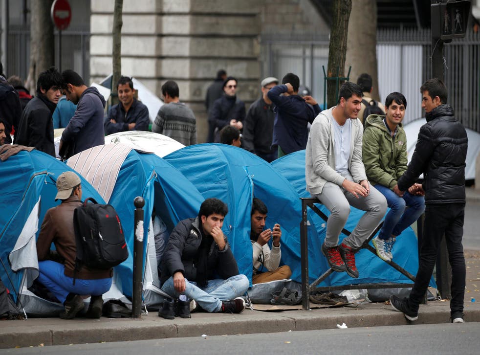 Migrants sit in their tents at a makeshift migrant camp on a street near the metro stations of Jaures and Stalingrad in Paris, France, October 28, 2016