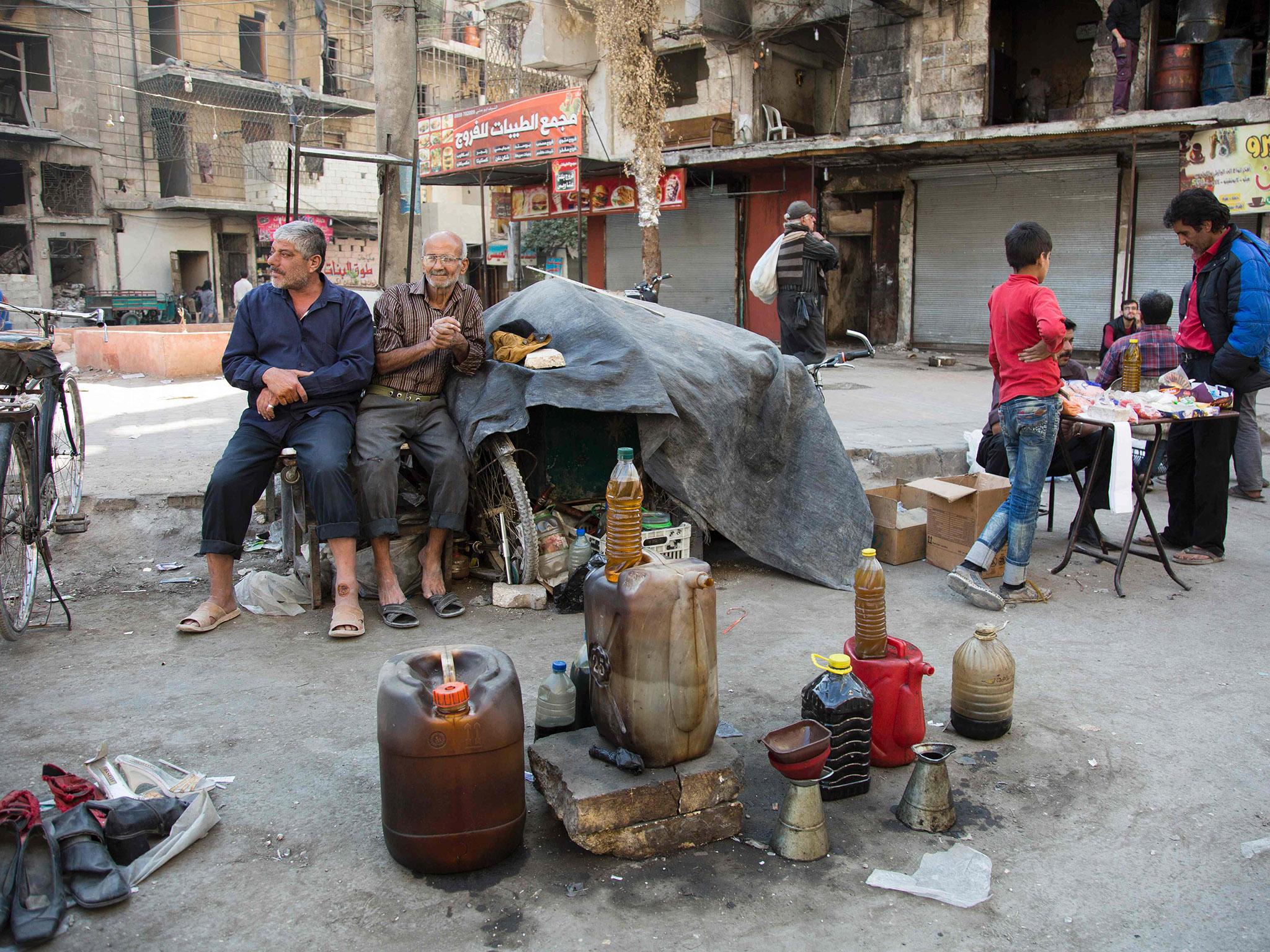 Syrian men sell fuel produced from plastic in the rebel-held side of the embattled northern city of Aleppo