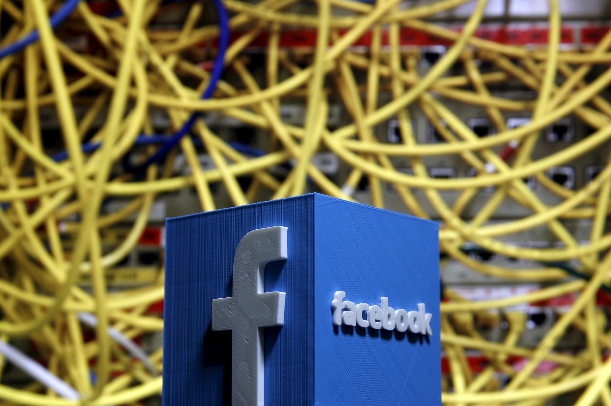 A 3D plastic representation of the Facebook logo is seen in front of displayed cables in this illustration in Zenica, Bosnia and Herzegovina May 13, 2015
