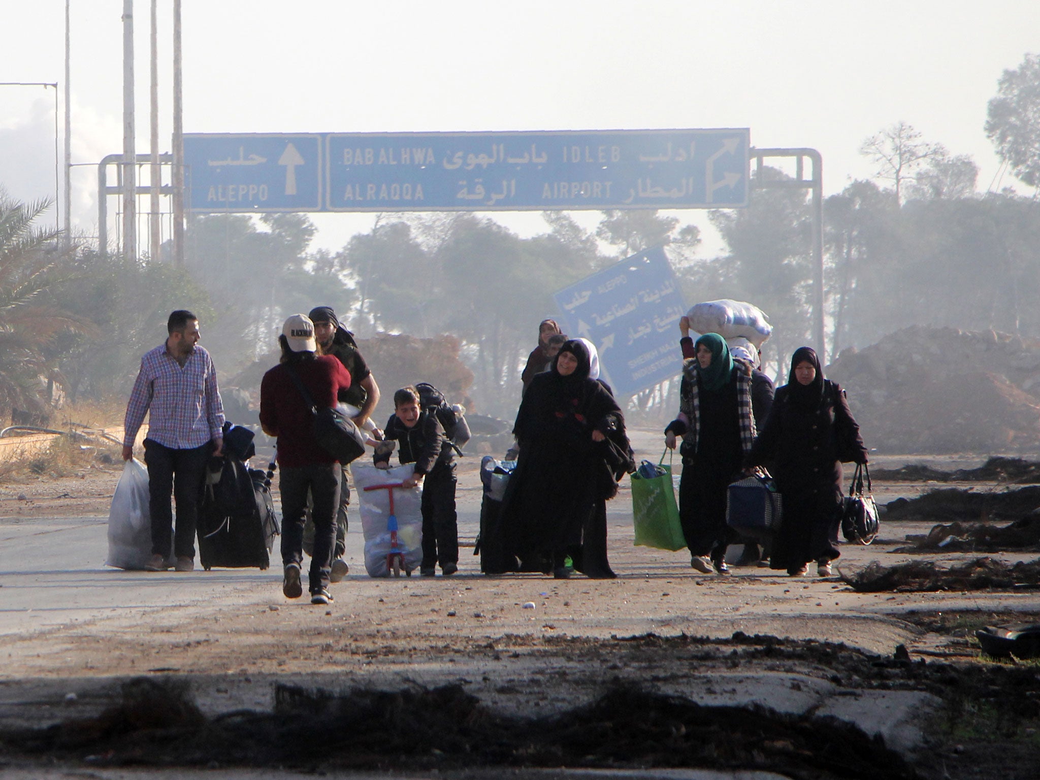 Syrians carry their belongings as they leave Aleppo’s southwestern frontline neighbourhood of Dahiyet al-Assad on Sunday