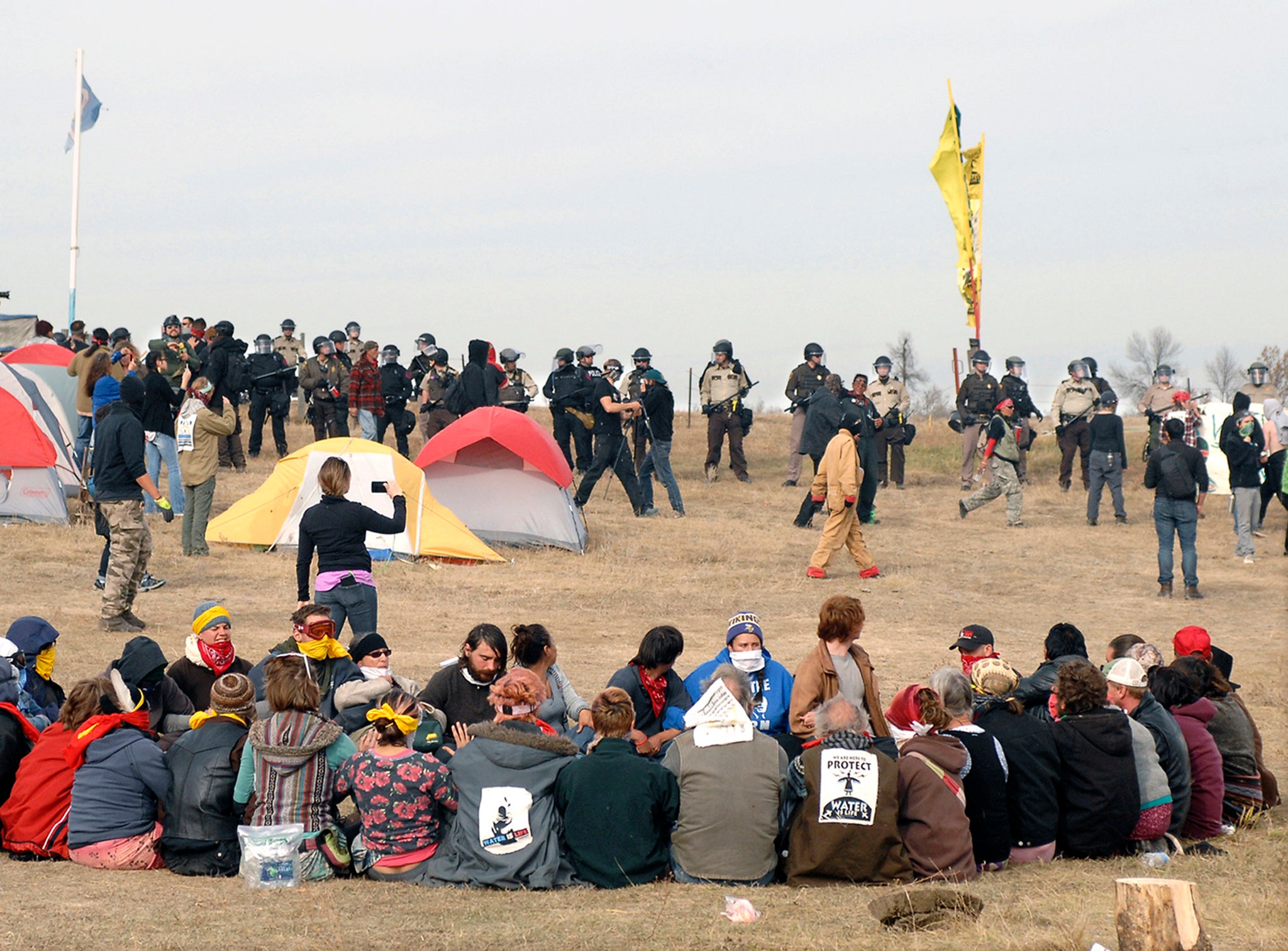 Dakota Access Pipeline protesters sit in a prayer circle at the Front Line Camp as a line of law enforcement officers attempt to relocate campaigners off the site