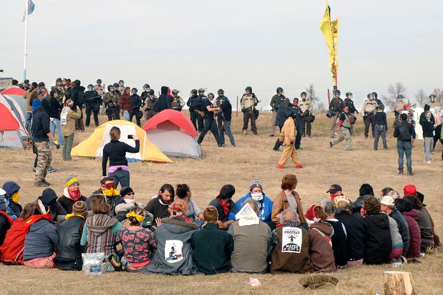 Dakota Access Pipeline protesters sit in a prayer circle at the Front Line Camp as a line of law enforcement officers attempt to relocate campaigners off the site