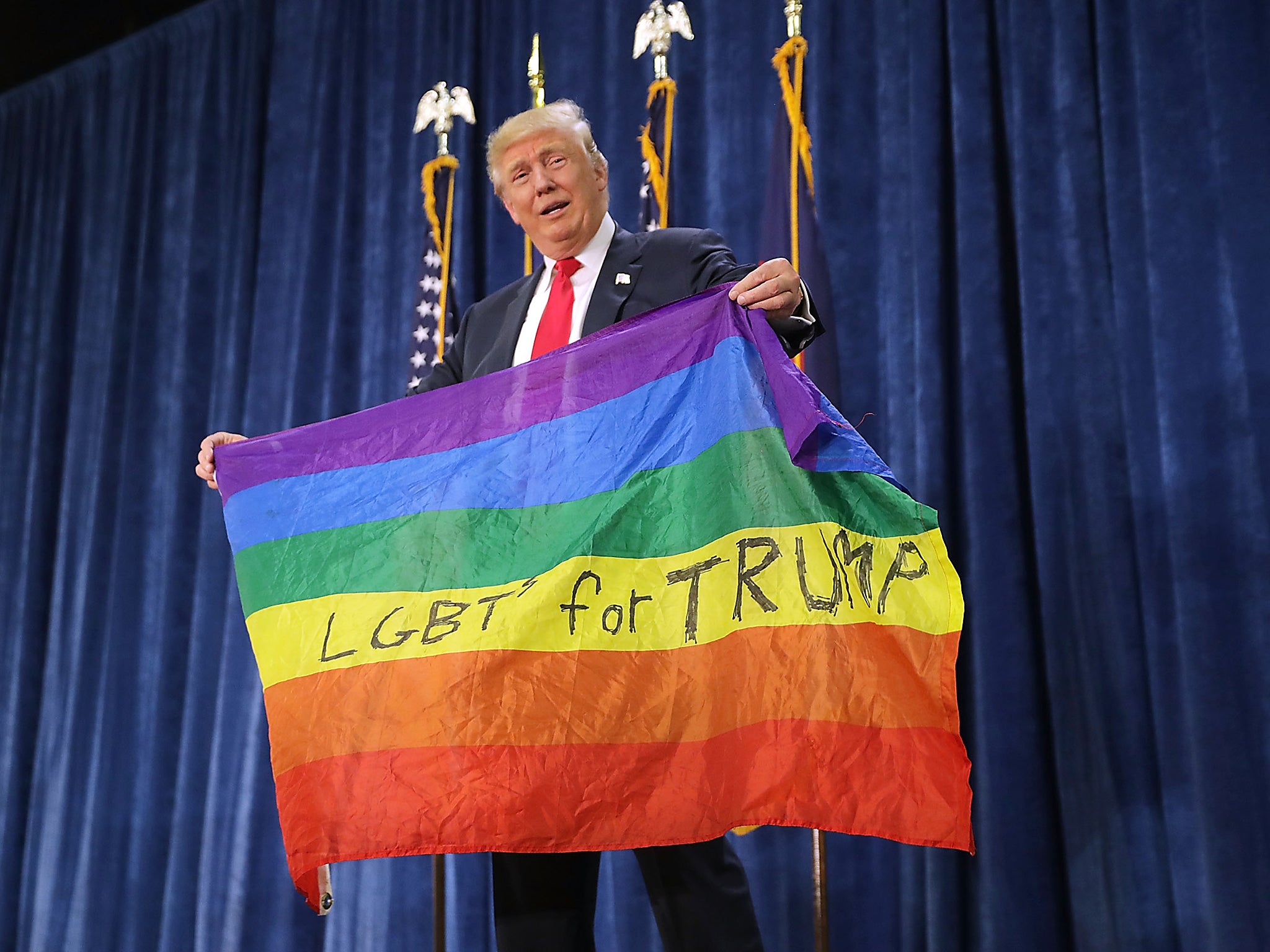 Republican presidential nominee Donald Trump holds a rainbow flag