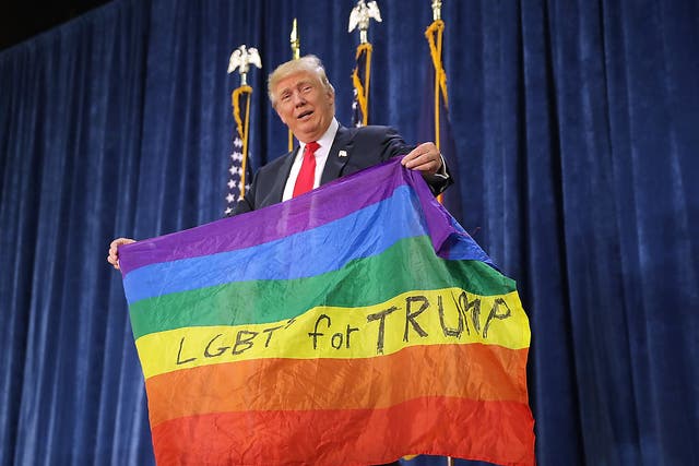 Republican presidential nominee Donald Trump holds a rainbow flag
