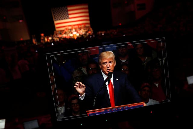 Republican presidential nominee Donald Trump appears on a video screen as he holds a rally with supporters in Bangor, Maine