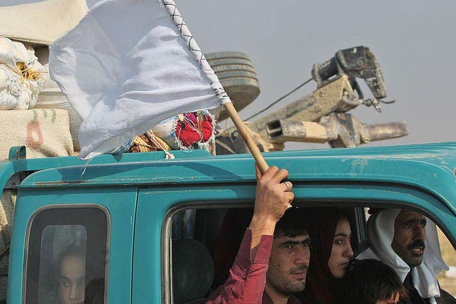 An Iraqi man waving a white flag sits with his family in a vehicle driving near Sin al-Dhuban after they fled the Hammam al-Alil area on October 27, 2016