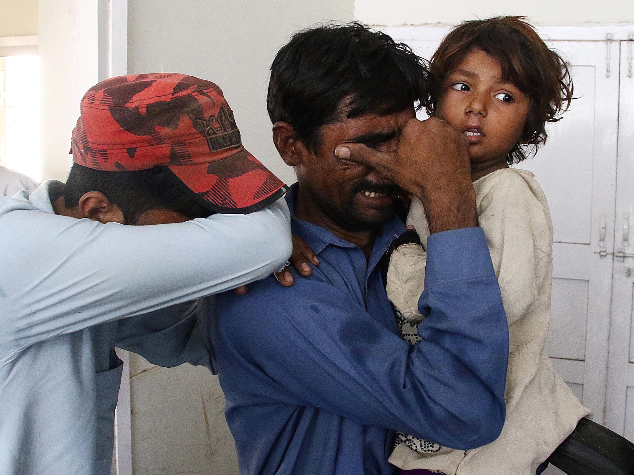 Relatives react after identifying the bodies of their loved ones at a mortuary after two railway trains collided in Karachi