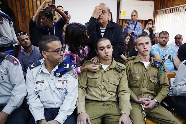 The father of Israeli soldier Elor Azaria, who is charged with manslaughter by the Israeli military after he shot a wounded Palestinian assailant as he lay on the ground in Hebron, prays behind him in a military court during a remand hearing for his case, near the southern Israeli city of Kiryat Malachi
