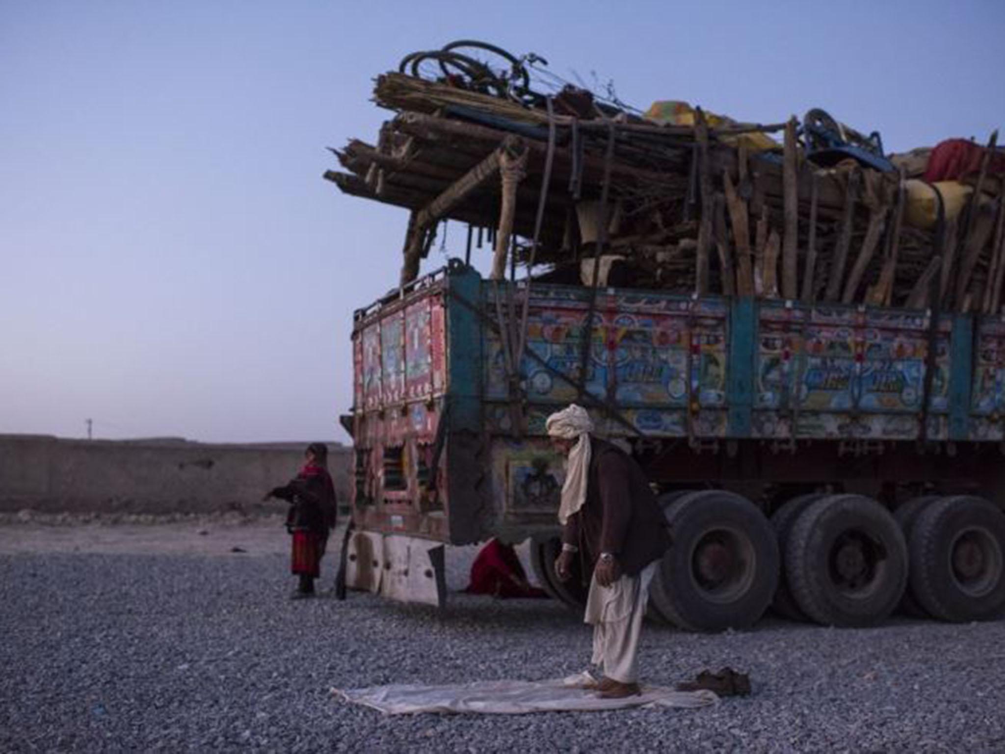 A man prays beside the truck that carried him and his family to the centre