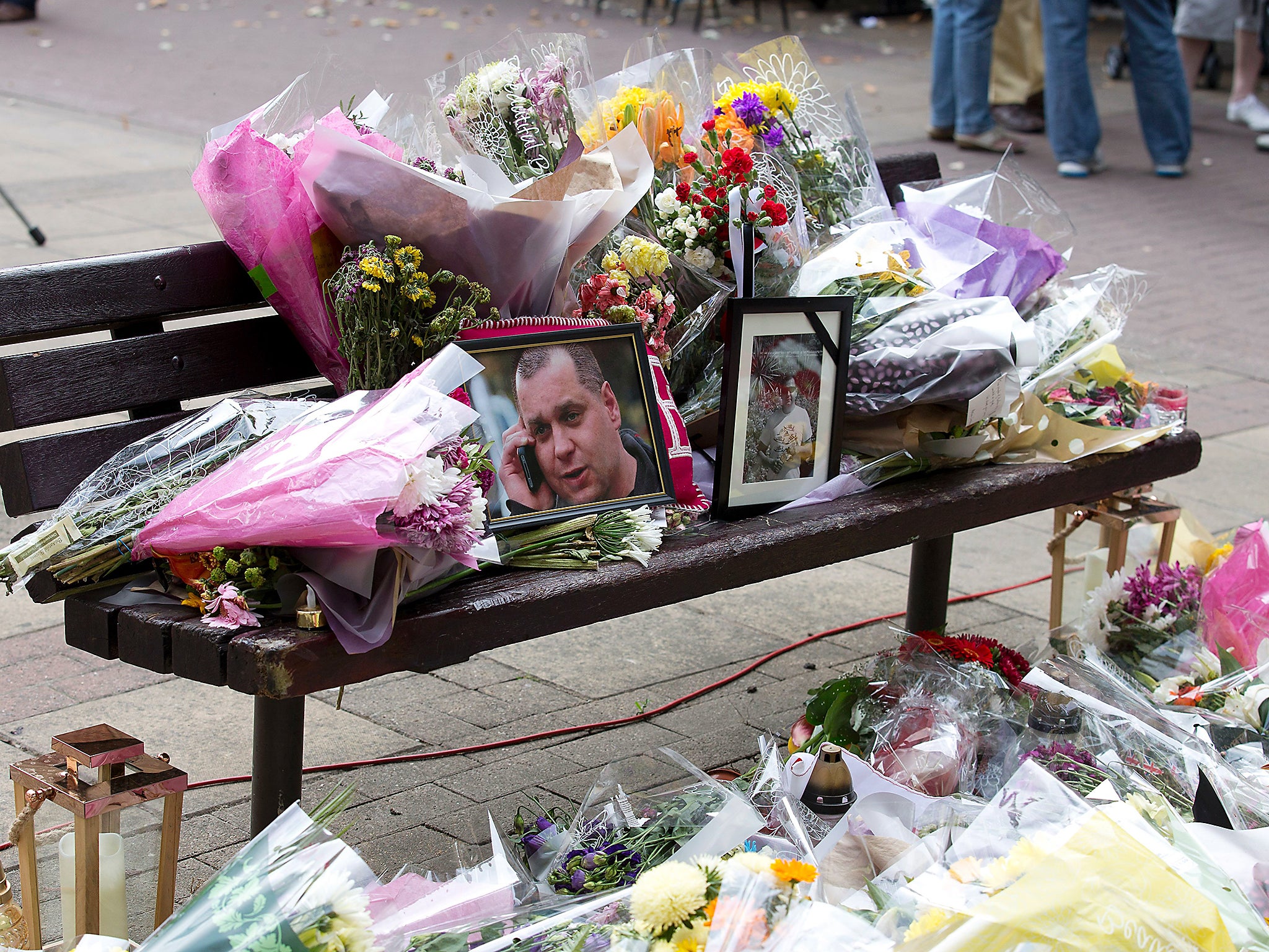 Floral tributes and a photograph of Arek Jozwik are seen on a bench at the shopping centre where he was killed, in Harlow, Essex