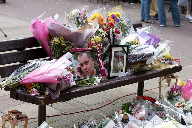 Floral tributes and a photograph of Arek Jozwik are seen on a bench at the shopping centre where he was killed, in Harlow, Essex