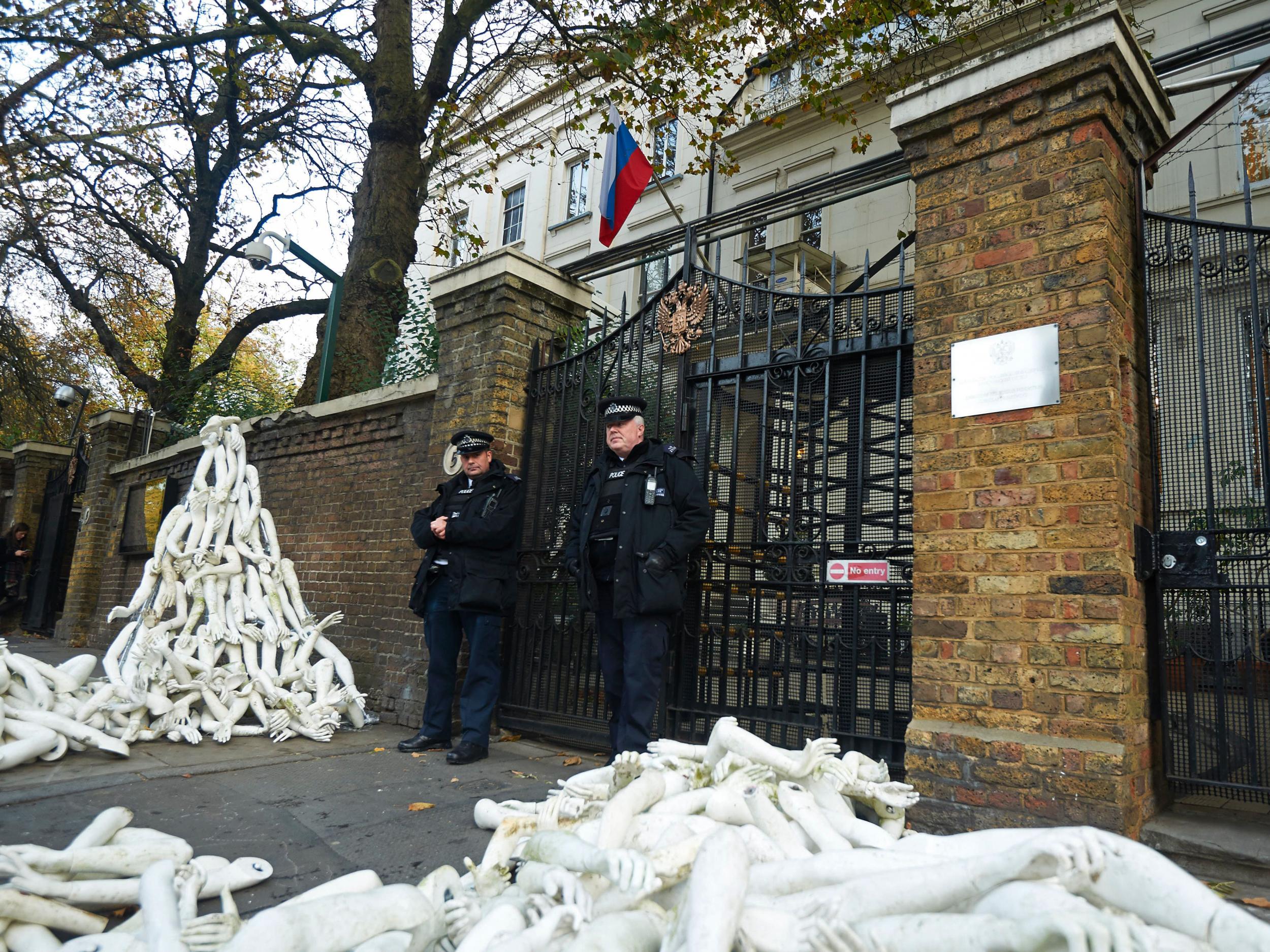 Police stand guard as structures made from white mannequin limbs are pictured outside the Russian embassy in west London