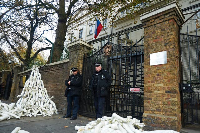 Police stand guard as structures made from white mannequin limbs are pictured outside the Russian embassy in west London