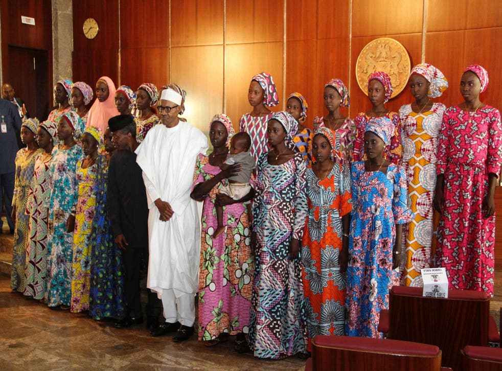 Nigerian President Muhammadu Buhari poses with the 21 Chibok girls who were released by Boko Haram in October