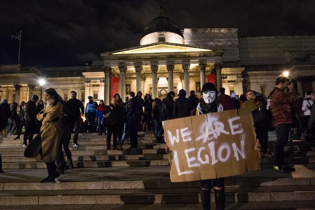 masked protester holds a sign which reads 'We Are Legion' in Trafalgar Square during the Million Mask March on November 5, 2016 in London