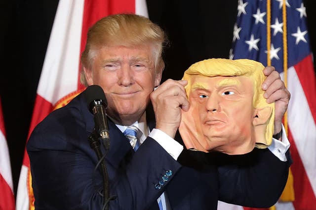 Donald Trump posing with a mask of his face tossed on stage by a supporter in Florida <em>Chip Somodevilla/Getty</em>