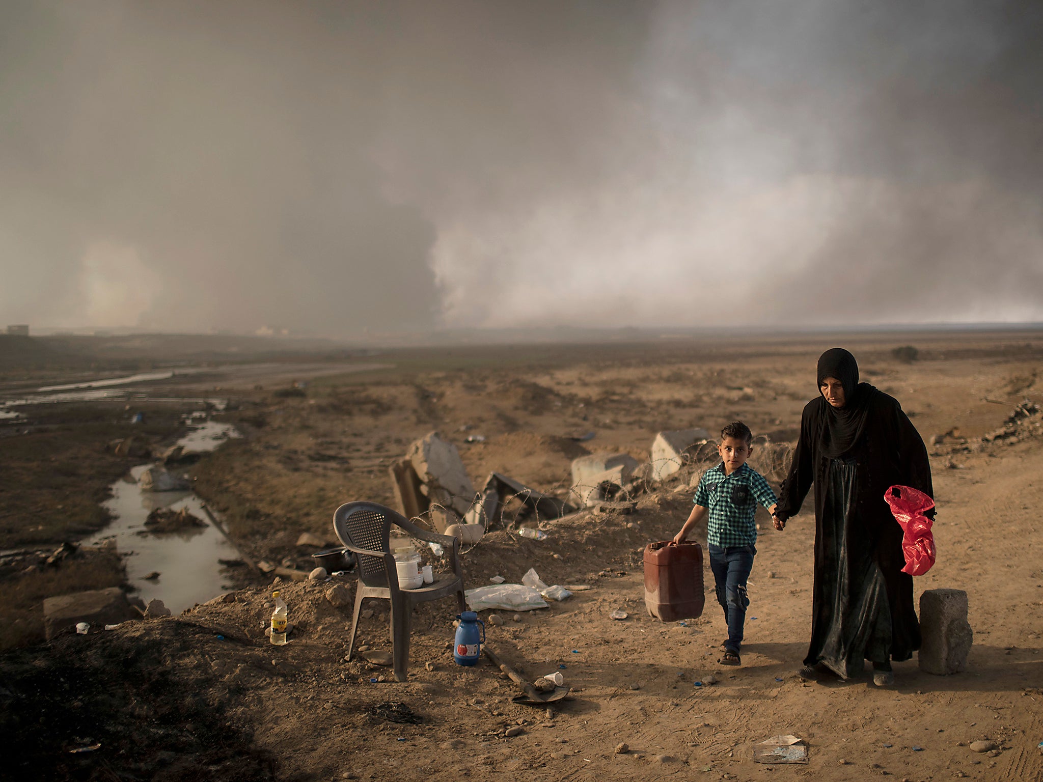 Displaced people walk past a checkpoint near Qayara, south of Mosul, Iraq