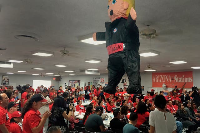 Members of the Culinary Workers Union Local 226, cheer during a rally under a Donald Trump pinata in Las Vegas