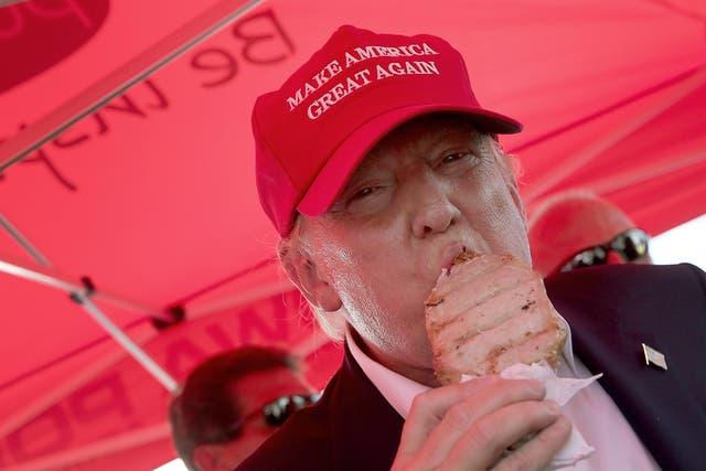 Republican presidential candidate Donald Trump eats a pork chop on a stick and gives a thumbs up sign to fairgoers at the Iowa State Fair