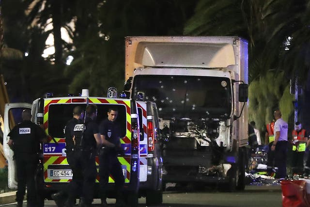 Police officers and rescue workers stand near a van that ploughed into a crowd leaving a fireworks display in the French Riviera town of Nice