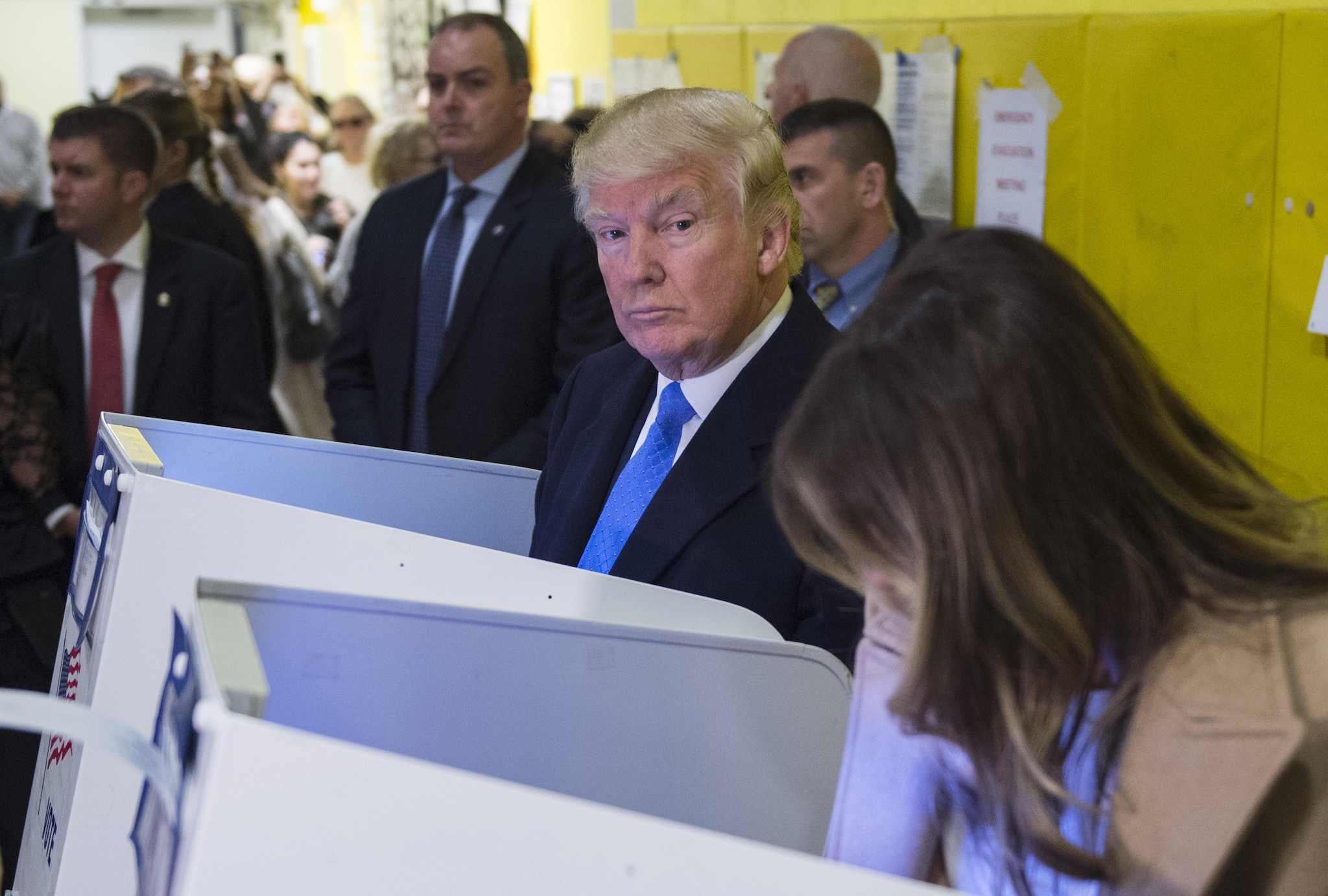 Republican presidential nominee Donald Trump(2nd R) and his wife Melania fill out their ballots at a polling station in a school during the 2016 presidential elections on November 8, 2016 in New York