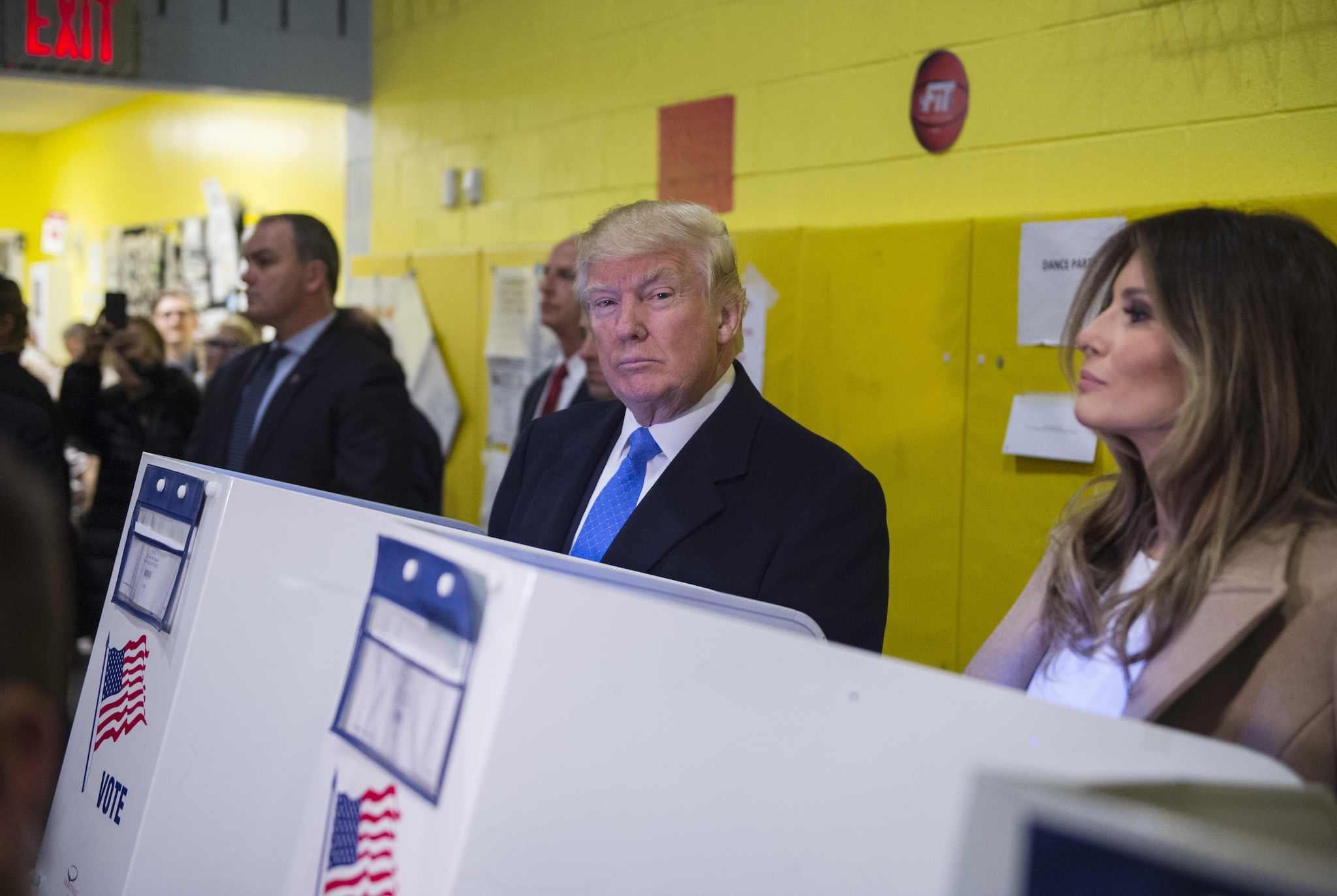 Republican presidential nominee Donald Trump(2nd R) and his wife Melania fill out their ballots at a polling station in a school during the 2016 presidential elections