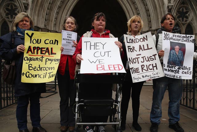 Demonstrators hold placards as they gather to protest against government changes to the welfare system and the proposed 'Bedroom Tax' in 2013