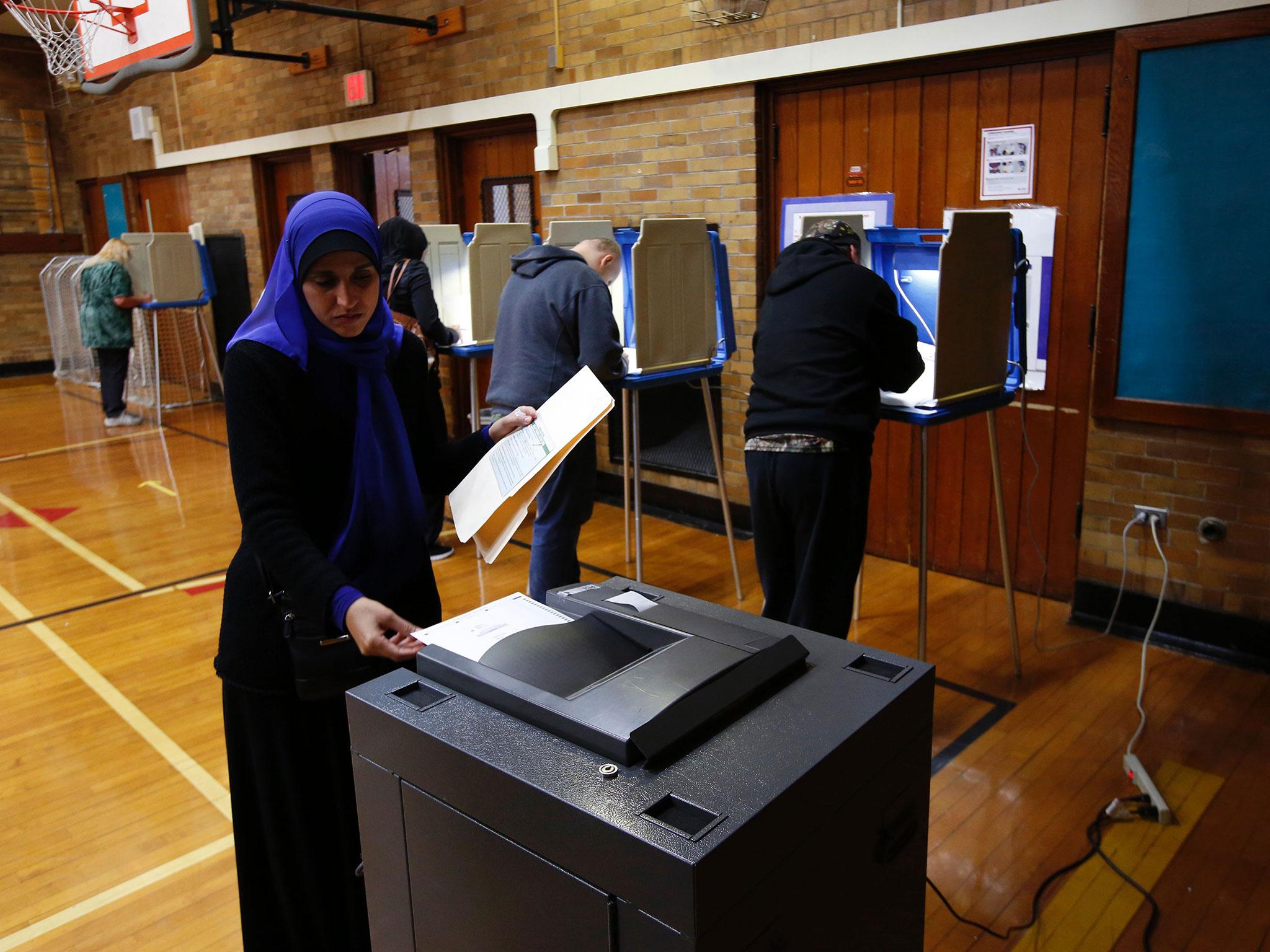 A Muslim woman puts her ballot in the scanner to be tabulated after voting at Oakman Elementary School during the US presidential election on 8 November, 2016 in Dearborn, Michigan