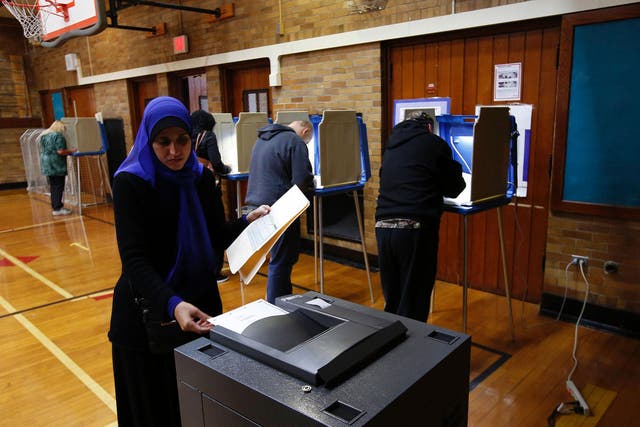 A Muslim woman puts her ballot in the scanner to be tabulated after voting at Oakman Elementary School during the US presidential election on 8 November, 2016 in Dearborn, Michigan