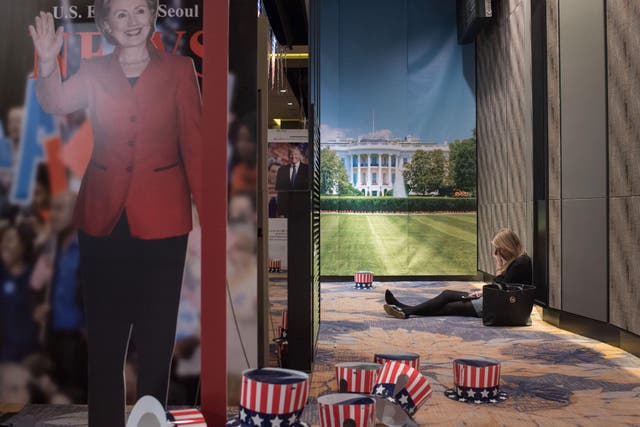 A woman sits on the floor behind a cut-outs of US presidential nominees Hillary Clinton and Donald Trump at an election event organised by the US embassy, at a hotel in Seoul on November 9, 2016 ED JONES/AFP/Getty Images