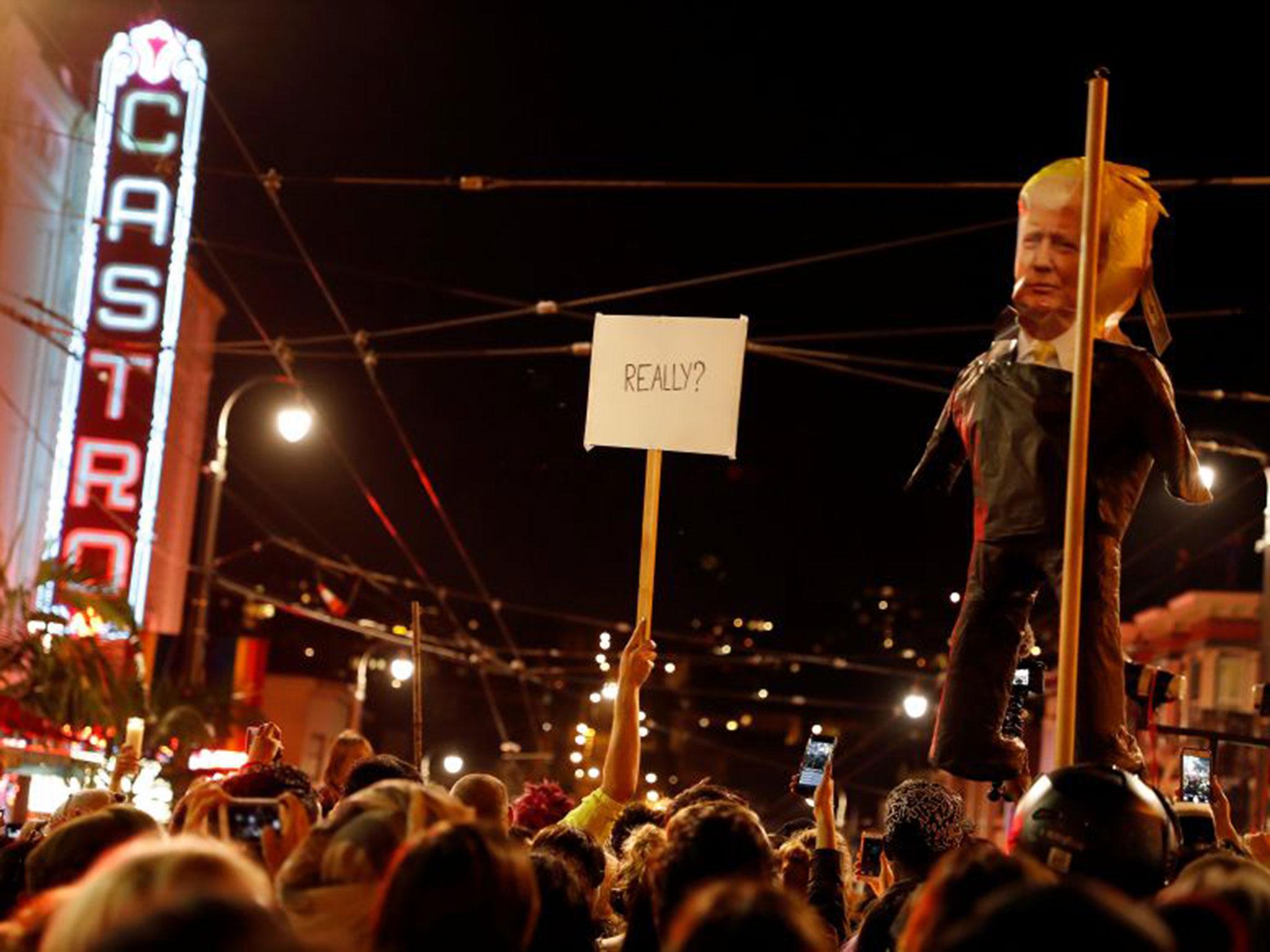 A demonstrator holds a sign next to a pinata depicting Donald Trump during a demonstration in San Francisco, California