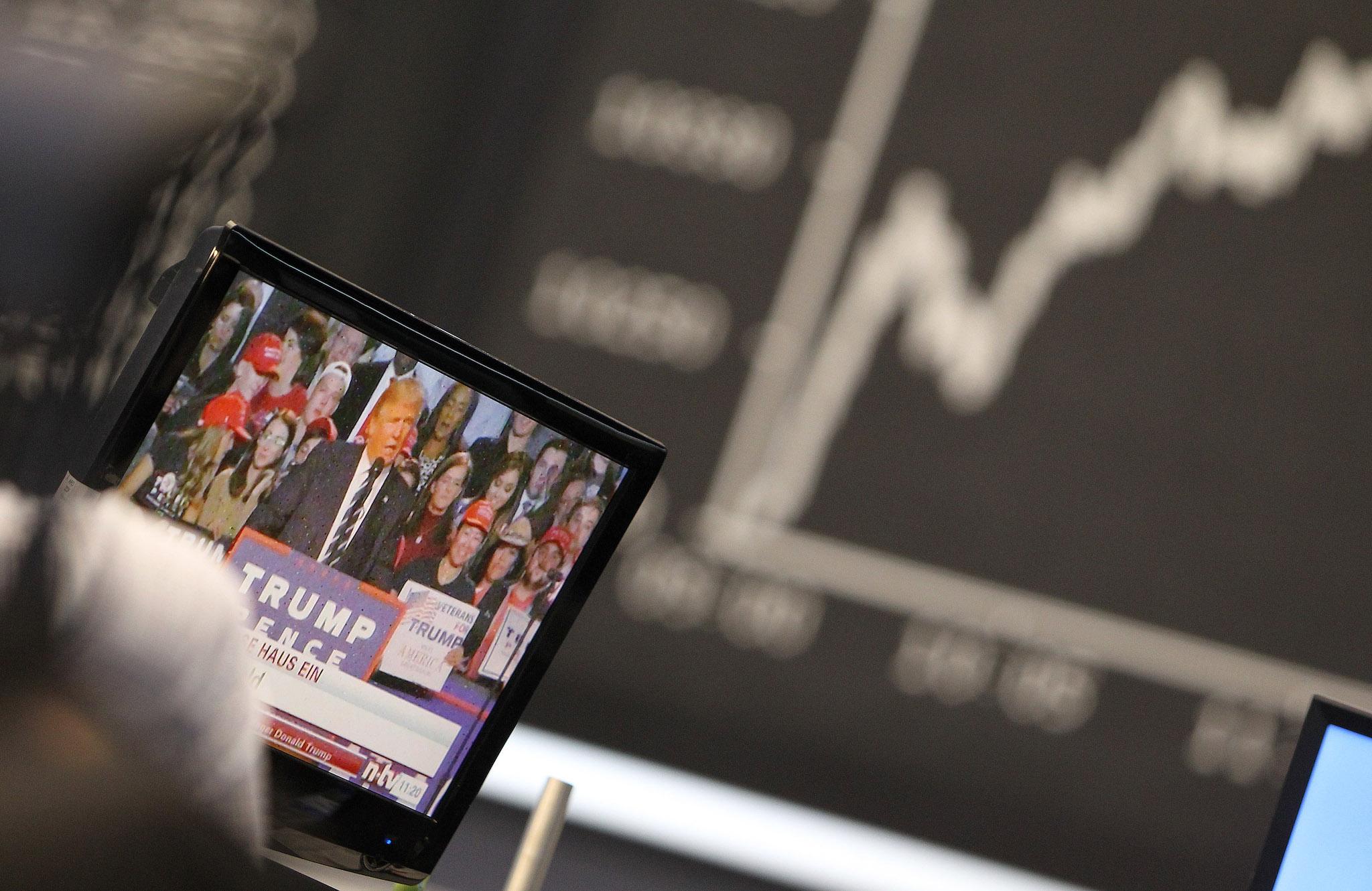 A display showing the German Stock Market Index DAX is pictured at the stock exchange in Frankfurt, Germany, on November 9, 2016 as the Tv screens shows the results of presidential elections in US