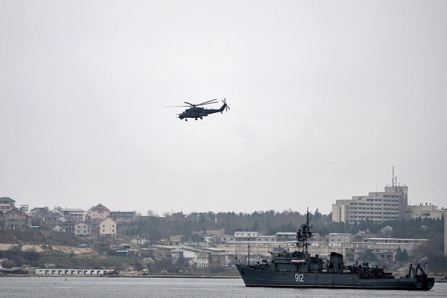 A Russian Mi24 military helicopter flies over the Russian navy minesweeper ship 'Turbinist' in the harbour of Sevastopol