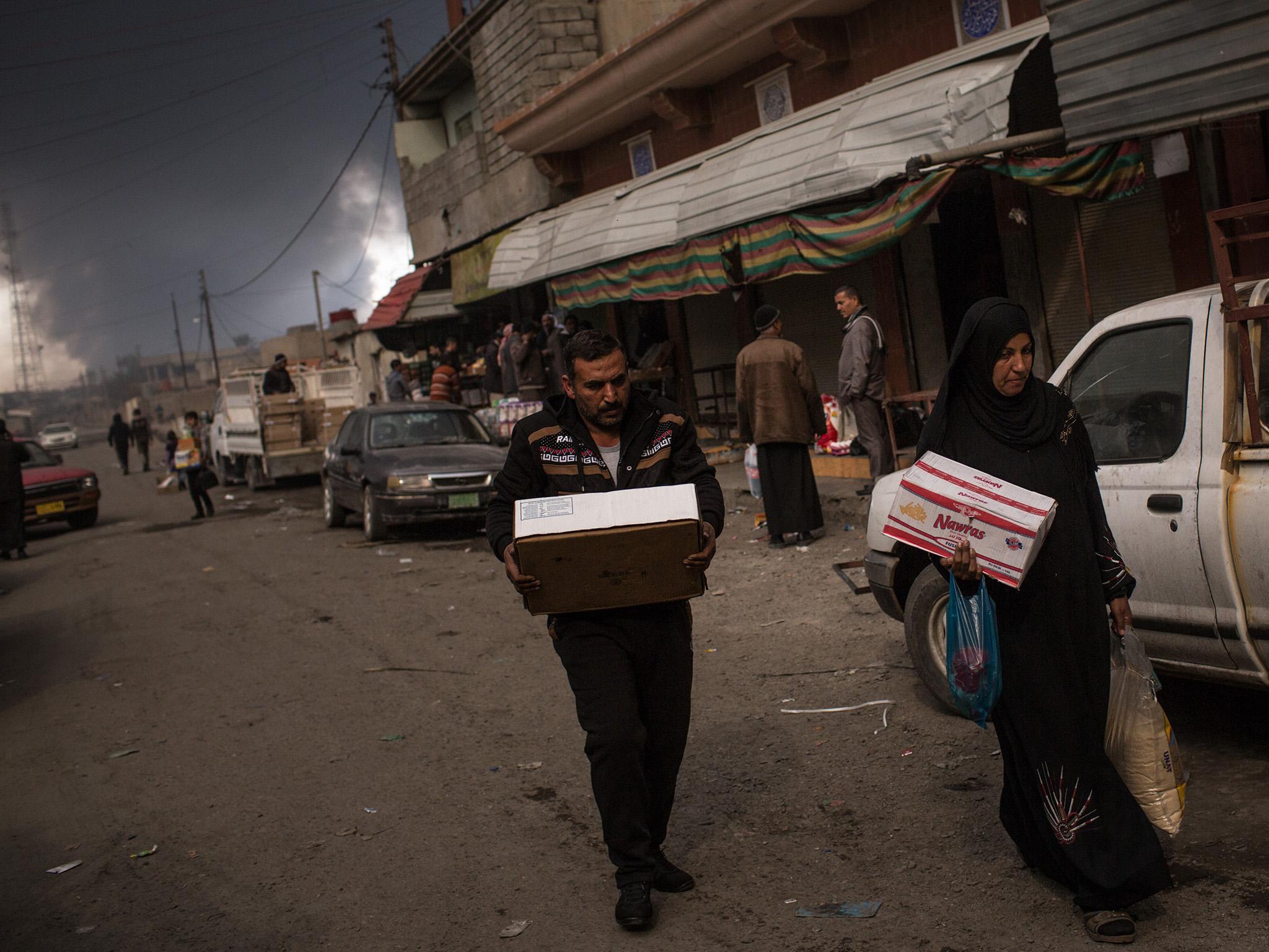 People shopping at the local market; smoke from a burning oil fills the sky