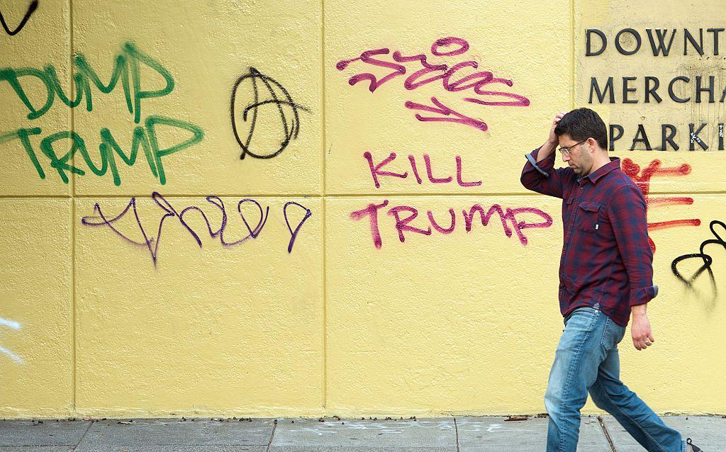 A man walks by graffiti against President-elect Donald Trump in downtown Oakland, California
