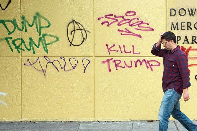 A man walks by graffiti against President-elect Donald Trump in downtown Oakland, California