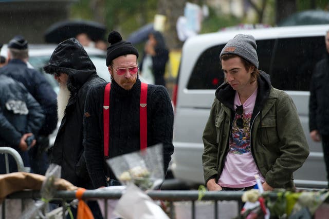 Jesse Hughes (centre) with Eagles of Death Metal bandmate Julian Dorio (left) looking at tributes to victims of the attacks outside the Bataclan in December 2015