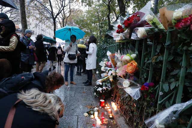 People gather around flowers and candles laid next to the Bataclan concert hall in Paris on November 12, 2016, a few hours before the reopening concert by British musician Sting to mark the first anniversary of the November 13 Paris attacks