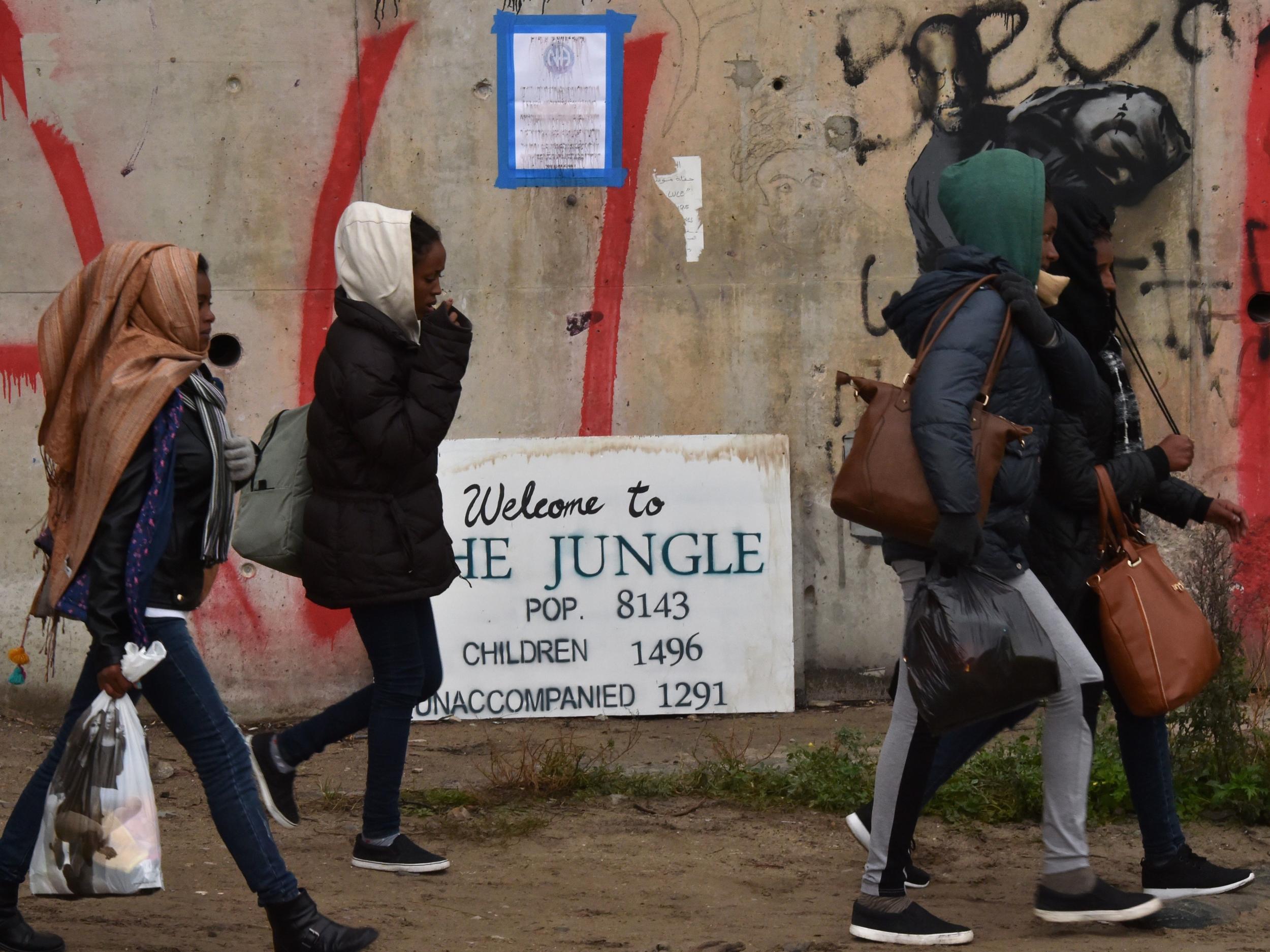 Refugee girls walk towards an official meeting point set by French authorities as part of the evacuation of the Calais Jungle on 24 October 2016