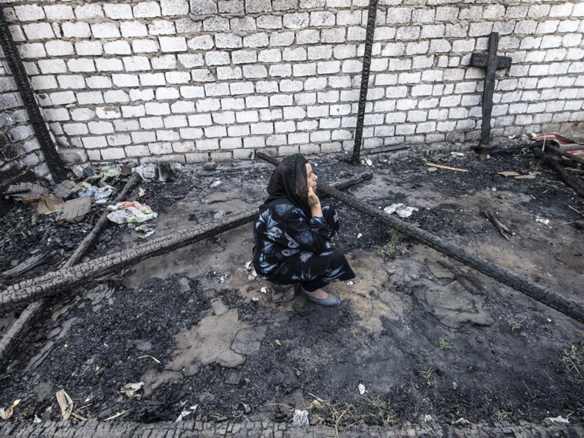 An Egyptian Coptic Christian woman sits in the rubble of a makeshift chapel that was torched a few months ago during clashes in the village of Ismailia, about 200 miles south of Cairo