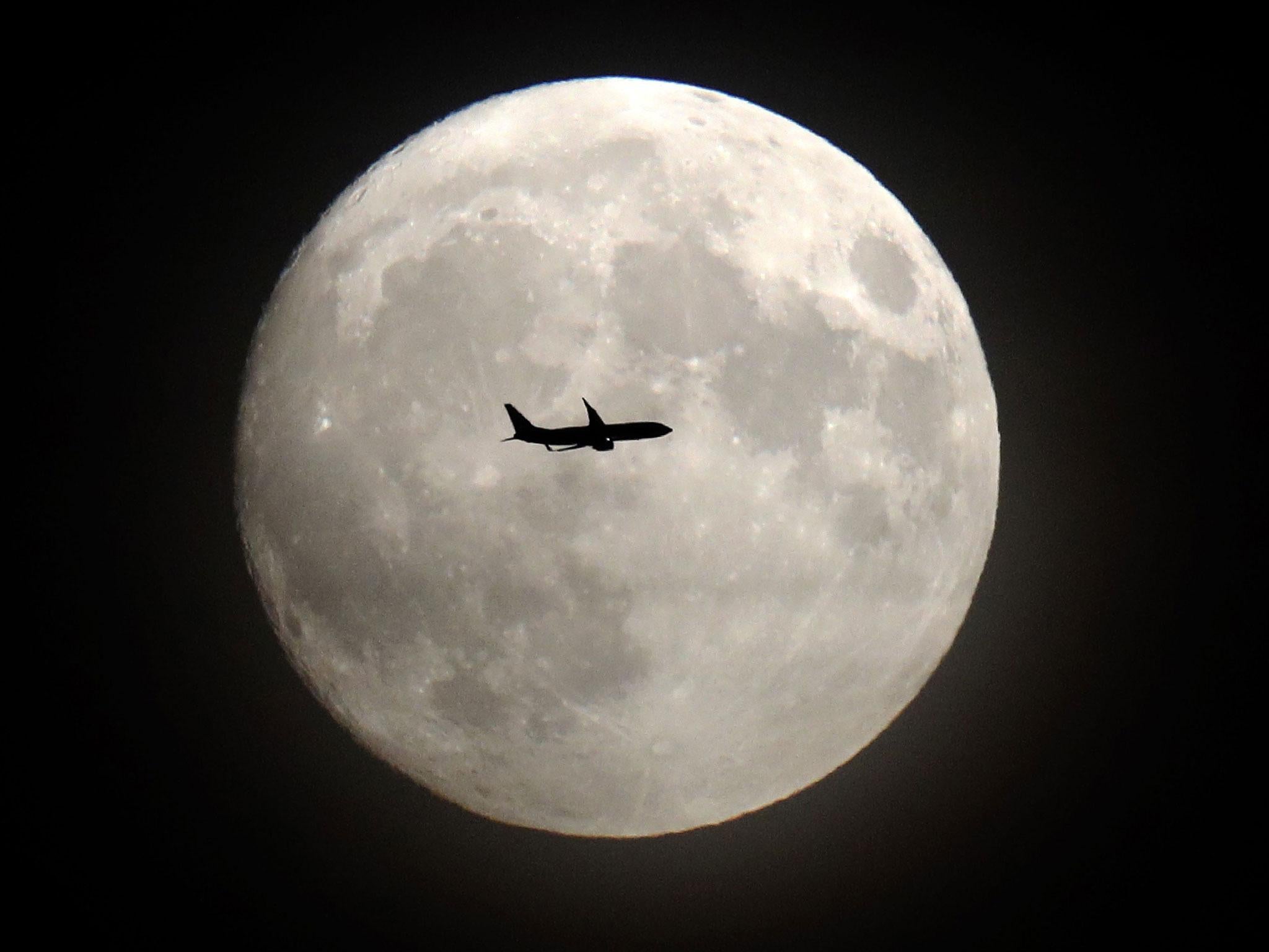 A commerical jet flies in front of the moon on its approach to Heathrow airport in west London on November 13, 2016.
