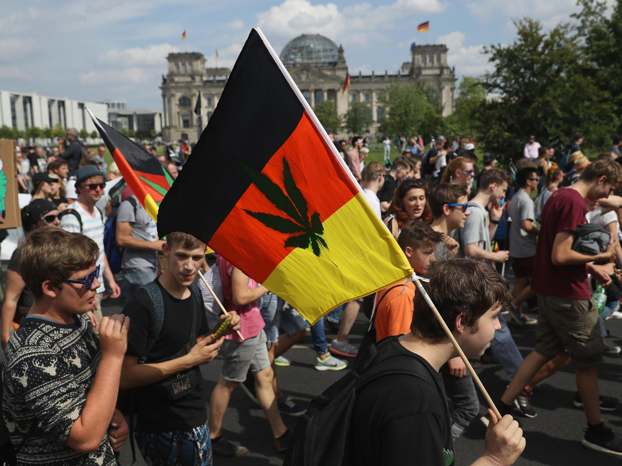 Activists, including two waving German flags that have a marijuana leaf painted on them, demand the legalisation of marijuana while marching past the Reichstag during the annual Hemp Parade (Hanfparade) on 13 August 2016 in Berlin