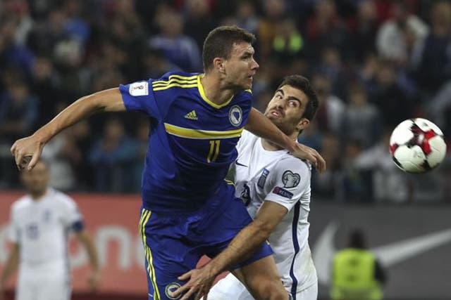 Dzeko jumps for the ball with Sokratis, whose shorts he later pulled down