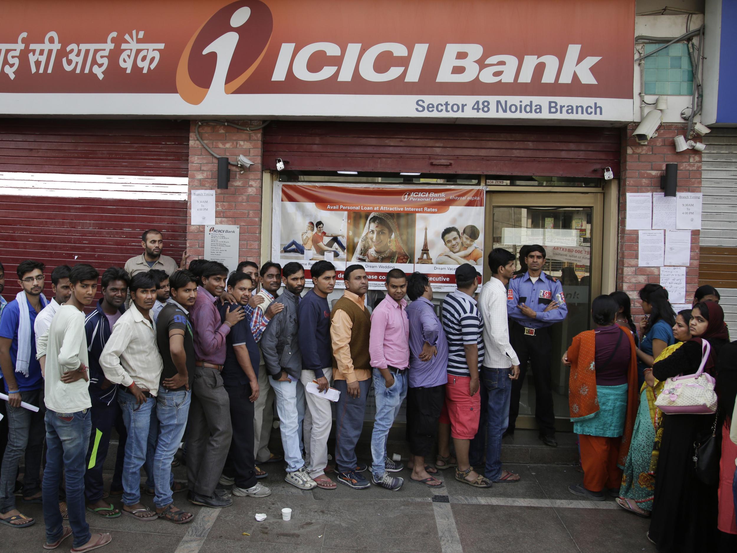 Indians queue to deposit and exchange discontinued currency notes outside a bank on the outskirts of New Delhi