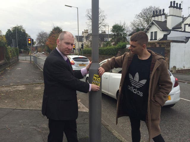 Liverpool councillor Patrick Hurley (left) and a colleague removing Nazi stickers which were spotted on lampposts and doors in Liverpool on Remembrance Sunday