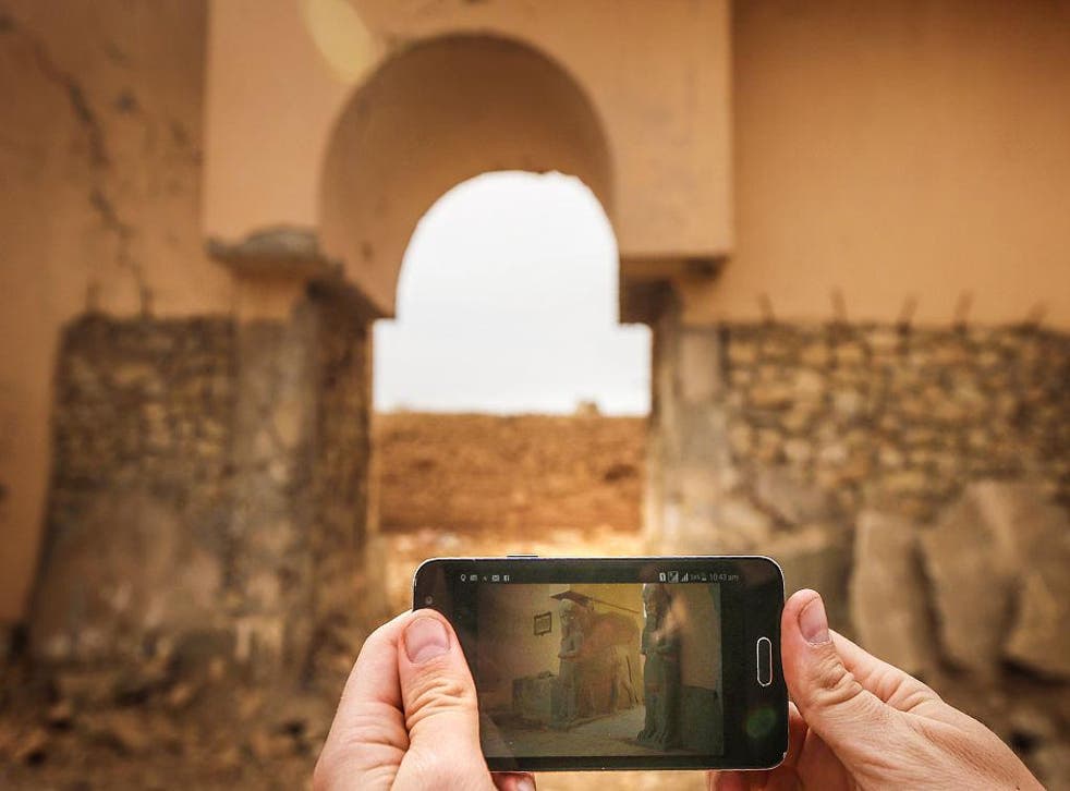 A mobile phone shows Nimrud as it was, in front of Nimrud as it is now