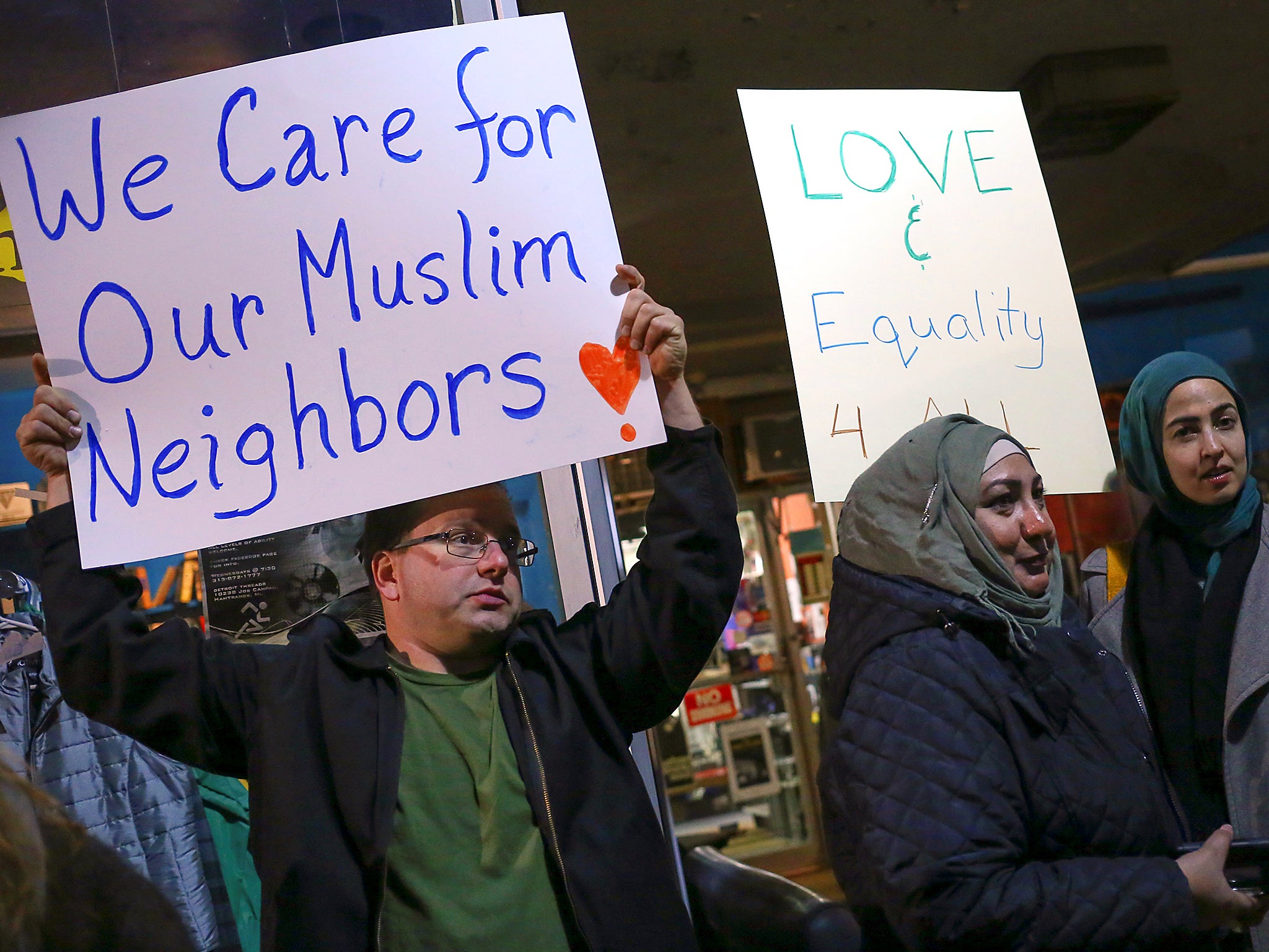 Demonstrators hold signs during a protest against President-elect Donald Trump and in support of Muslims residents in downtown Hamtramck, Michigan, U.S.